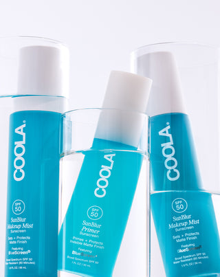 Three bottles of Coola Sunscreen products on a white background