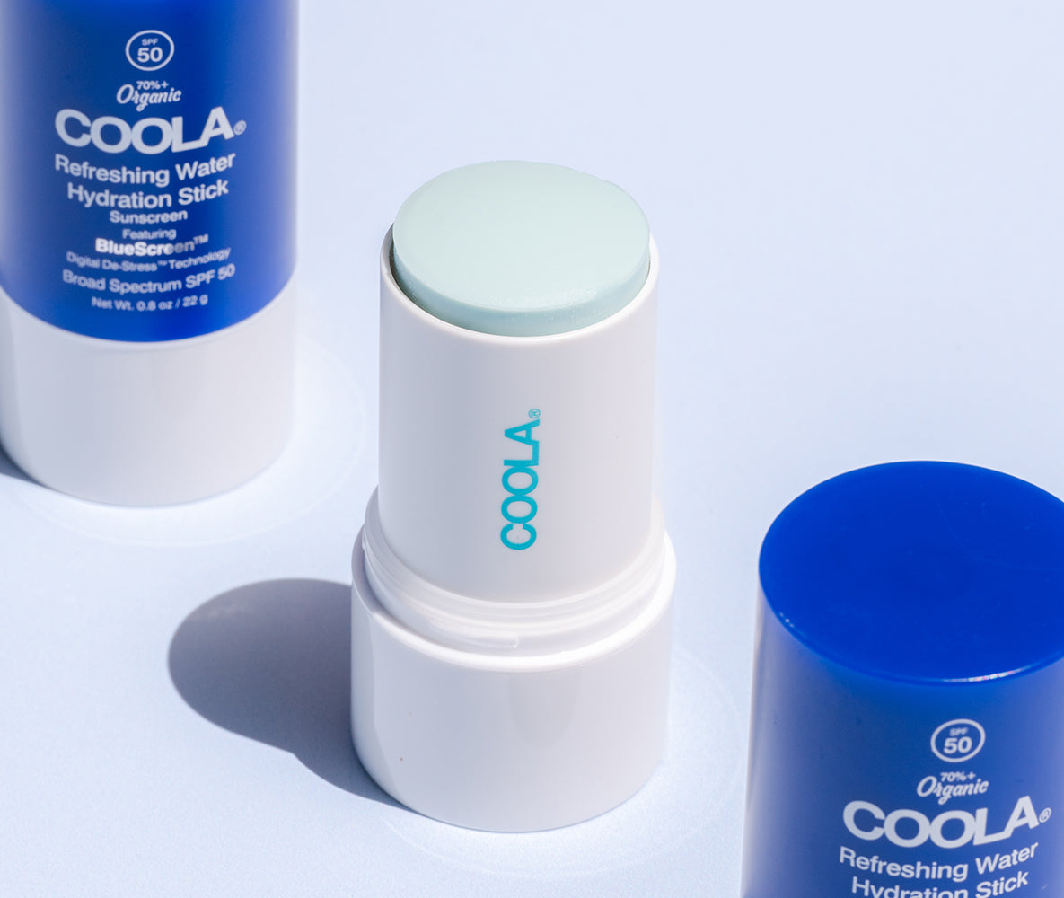 Three COOLA Refreshing Water Hydration Stick Sunscreens with SPF 50, one open to show the light blue stick.