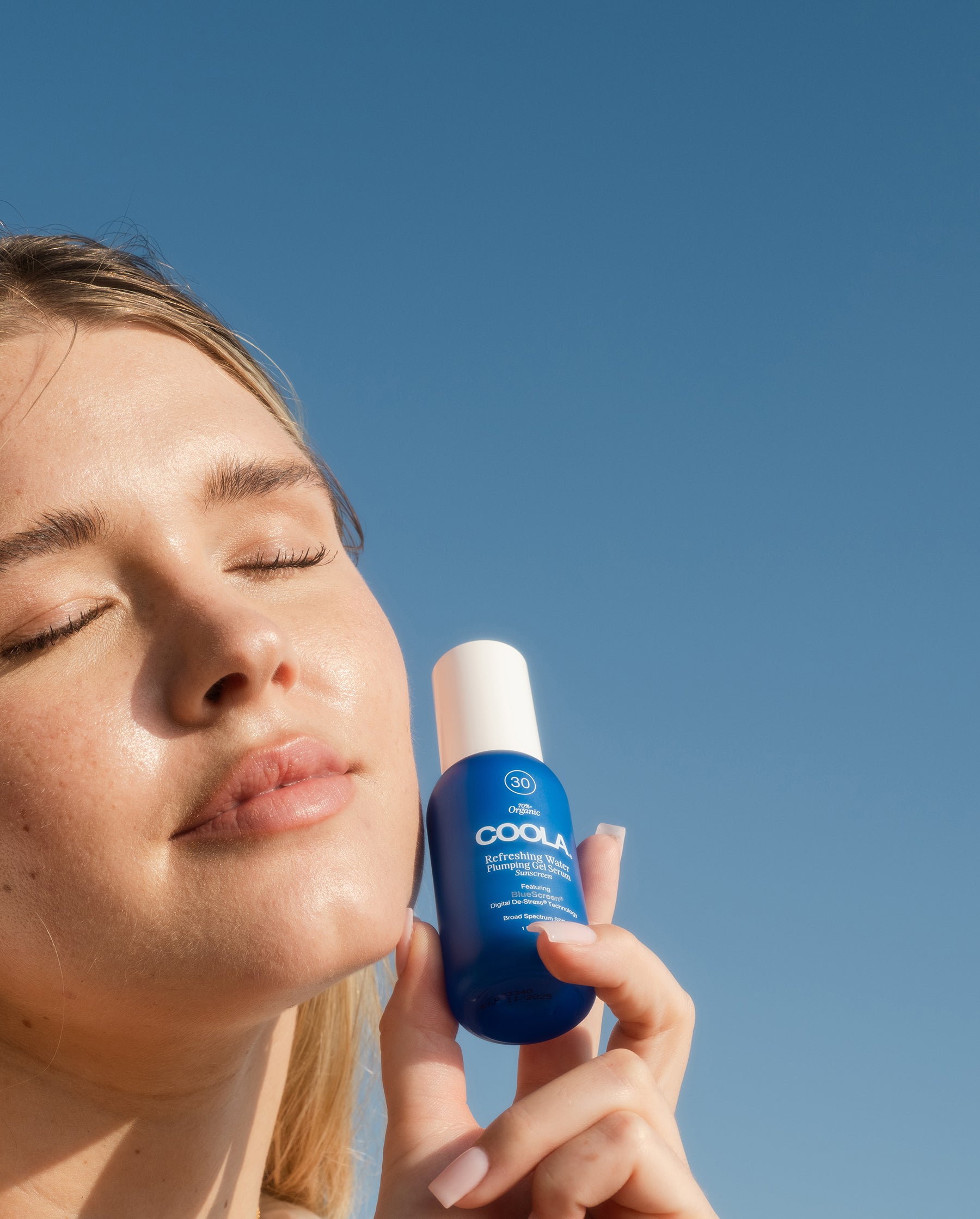 woman holding blue sunscreen next to face