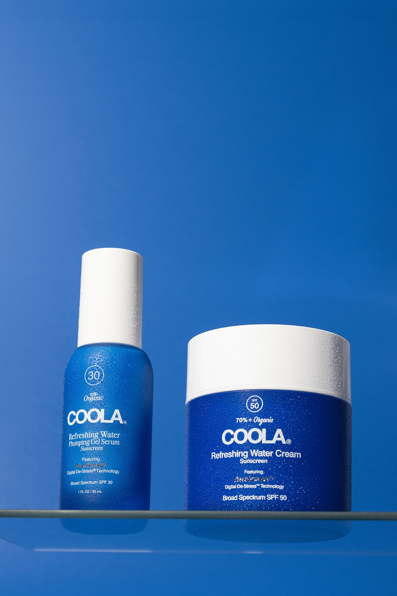 two blue sunscreen products sitting on glass shelf