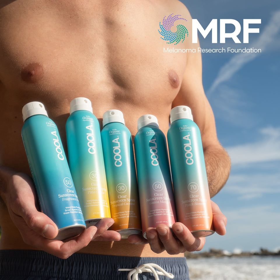 Man holding 5 Coola sunscreen sprays with sky in the background, featuring the MRF logo