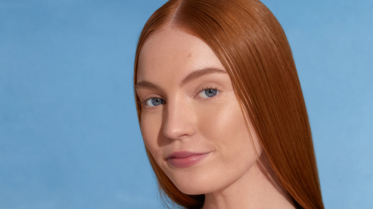 Model with long straight red hair against a blue background, without dew good applied.