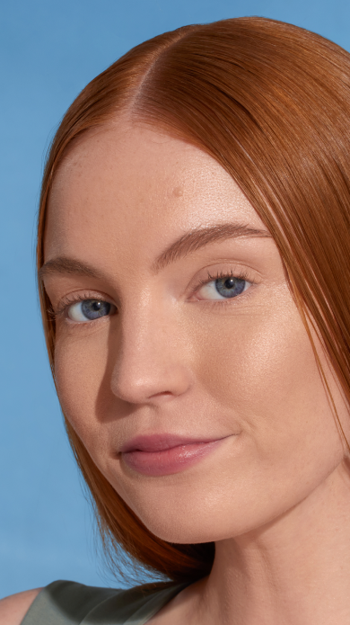 Model with long straight red hair against a blue background, without dew good applied.